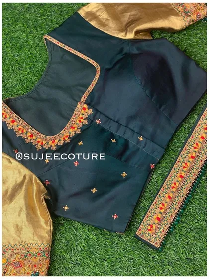 The front of a dark green blouse with contrasting gold sleeves. The simple sweetheart neckline is accented with a touch of red and orange embroidery.
