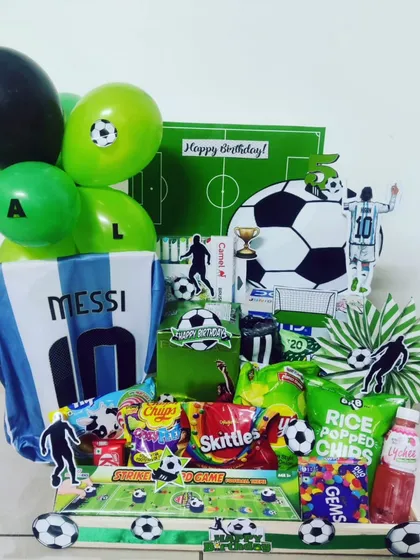 For the ultimate sports fan, I create theme-based hampers that celebrate their passion. This football-themed gift box for a Messi fan includes an Argentina jersey, themed snacks, balloons, and custom cutouts for a winning birthday surprise.