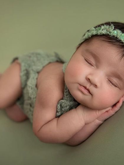 A close up of the side pose on the green backdrop, capturing the baby's perfect, smooth skin and peaceful sleep.
