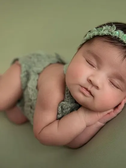 A close up of the side pose on the green backdrop, capturing the baby's perfect, smooth skin and peaceful sleep.
