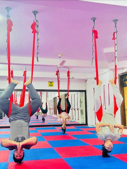 Inversions in aerial yoga are accessible and beneficial for everyone. This group of students is enjoying the spinal decompression and improved blood flow that comes from hanging upside down.