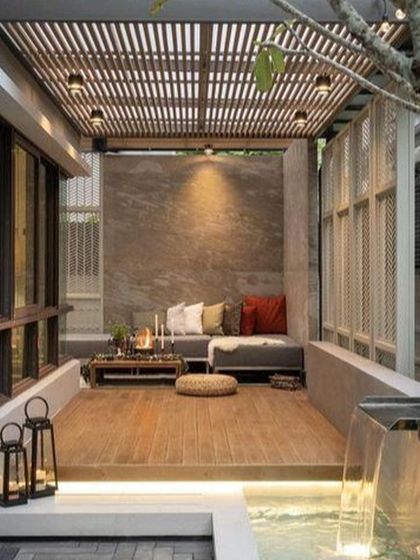 This cozy patio design is enhanced by a small, contemporary water feature next to the seating area. The sound of trickling water adds to the relaxing atmosphere of this intimate outdoor space.