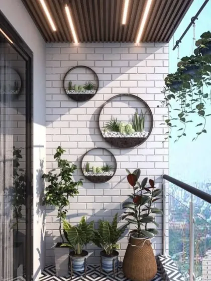 A bright and sunny balcony featuring a white brick wall adorned with circular wall planters. This design choice adds a playful and artistic touch, complemented by hanging vines and patterned floor tiles for a fresh, modern look.