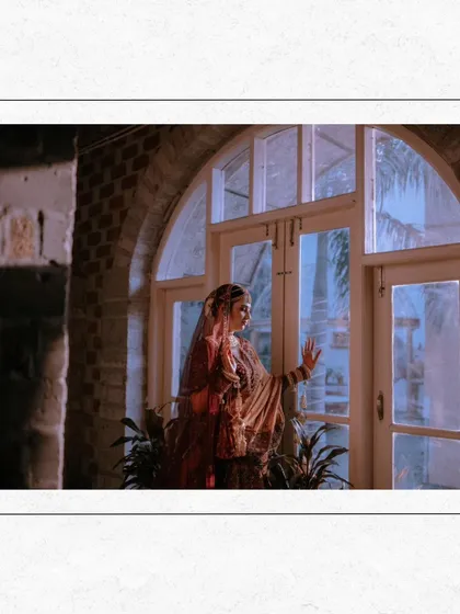 An artistic shot 얼굴 of Nisha looking out a window, the composition creating a sense of anticipation and quiet beauty.