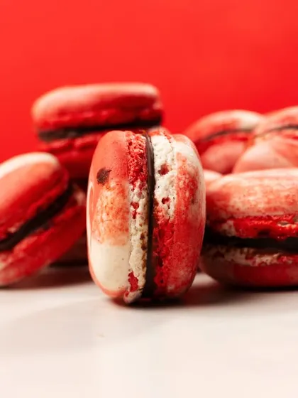 A pile of vibrant red macarons. The close-up shot emphasizes the delicate texture and rich color, making them look like little jewels.