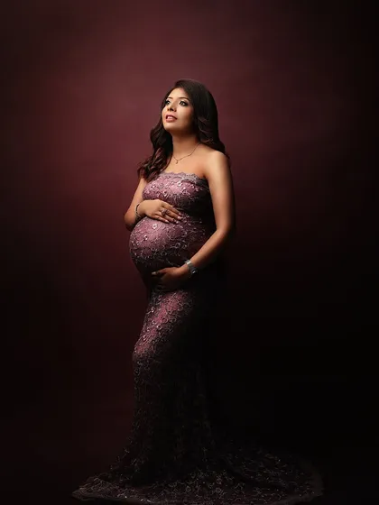 A classic maternity pose in a beautiful lace gown, looking up towards the light with a hopeful expression.