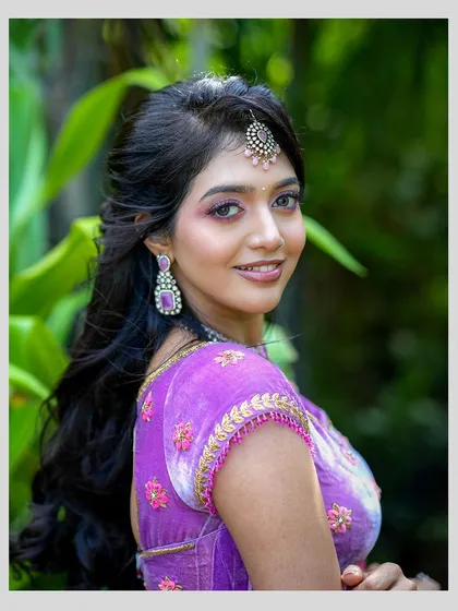 A close-up portrait showcasing the delicate floral embroidery on the lilac velvet blouse and the fine craftsmanship along the sleeve edges.