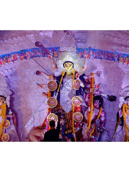 A devotee stands close to the Durga idol, offering prayers in a moment of quiet connection amidst the festival's buzz.