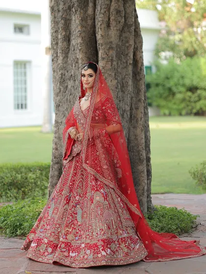 Walking towards forever. This bride looks absolutely regal in her traditional red lehenga, with makeup that enhances her natural beauty and gives her a timeless glow.