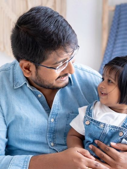 A quiet moment between father and child. The gentle smiles and eye contact in this portrait speak volumes about their special bond.