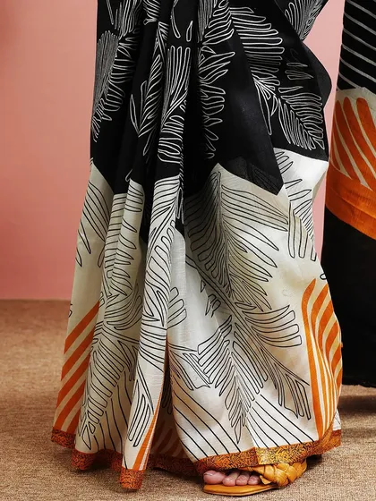 A modern black and white saree with a bold leaf print, accented with a touch of orange.
