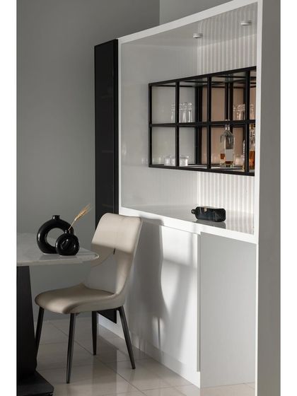 This detail shot highlights the custom bar and crockery unit. The design features a mix of open and closed storage, with a black metal grid shelf for displaying glassware, set against a white fluted backdrop.