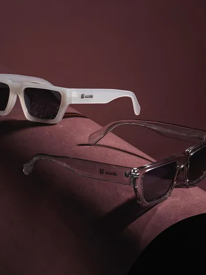 A sleek product shot of two pairs of modern sunglasses. The curved paper and focused lighting highlight the clean lines and transparent material of the frames.