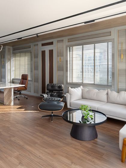 Natural light floods the executive cabin, highlighting the warm wood flooring and the comfortable seating area. This corner is perfect for informal discussions or a moment of quiet reflection during a busy day.