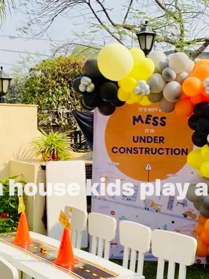 A close-up of the "Under Construction" party theme, with our white tables and chairs set against a themed backdrop and balloon arch.