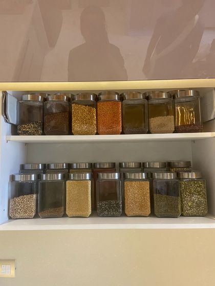 A clean and simple pantry cabinet with two shelves dedicated to different types of dals and grains. The uniform jars create a streamlined look that is easy to maintain.