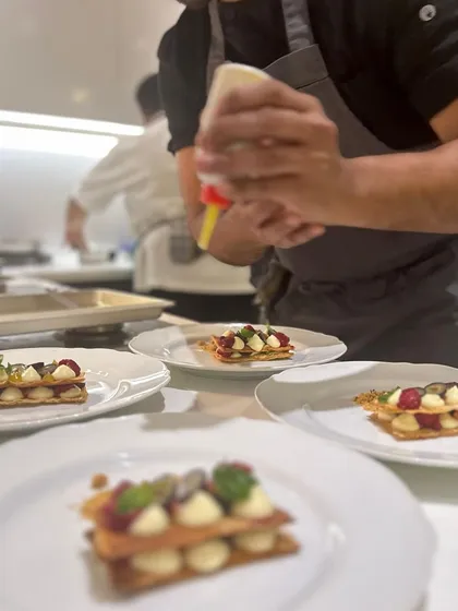 Adding a creamy element to a mille-feuille dessert. Each layer is carefully constructed.