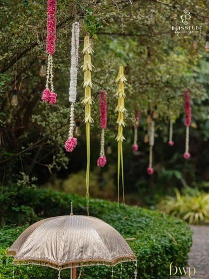 Details from a South Indian wedding decor, featuring hanging floral arrangements made of roses, jasmine, and coconut leaves. These traditional elements add fragrance and beauty to the atmosphere.