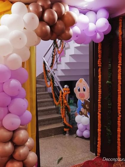 An entrance decoration for a baby shower. The pastel balloon arch in purple, pink, and brown creates a soft and inviting entryway for guests.