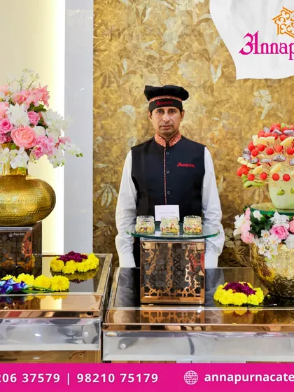 Our professional staff is ready to serve your guests with a smile. Here, a member of our team stands at a beautifully arranged grazing station, featuring fresh fruit skewers and other delectable appetizers.