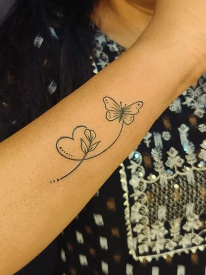 The color version of the heart, flower, and butterfly continuous line tattoo. The simple black lines make it a timeless piece.