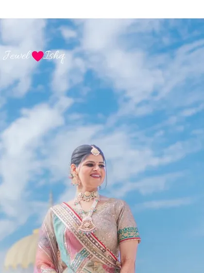A beautiful shot of the bride against a clear blue sky, her pastel jewellery and outfit creating a soft, dreamy look.