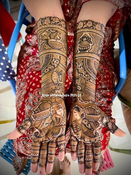 A full bridal design featuring custom portraits of the bride and groom on the palms. The arms are filled with traditional motifs like the kalash (pot) and peacocks, symbolizing prosperity and grace.
