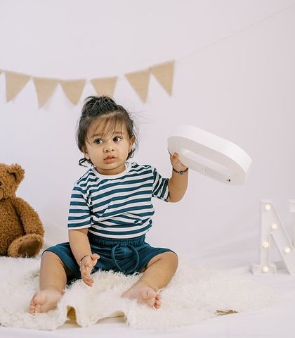 This little guy is ready for his pre-birthday shoot, surrounded by teddy bears and a festive "ONE" sign. I provide a variety of props to make your session special.