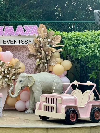 This pink safari theme features a large elephant prop next to a custom pink jeep, perfect for a little adventurer.
