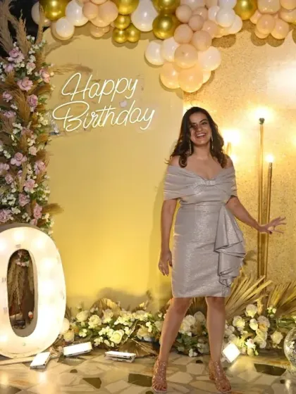 Another shot of the birthday girl enjoying her special night, posing in front of the custom-designed gold and floral backdrop.