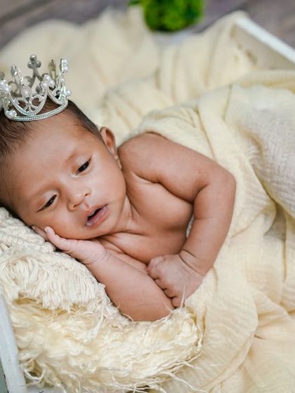 A little king on his throne. This simple, rustic setup uses a white wooden box, soft cream fabrics, and a touch of greenery for a natural and regal look.