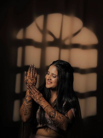 Another artistic shot of the bride, her smile and the detailed henna on her hands illuminated by a warm light.
