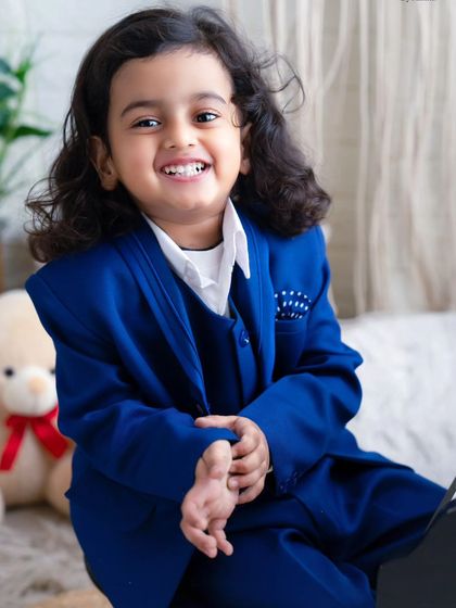 Hello handsome. This close-up portrait of a little boy in a blue suit captures his bright, happy smile and charming personality.