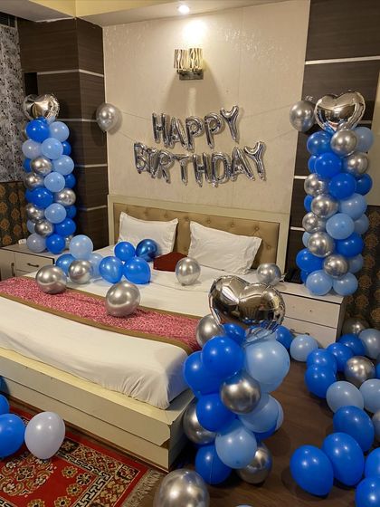 A close-up of the bed decoration with blue and silver balloon pillars and heart-shaped foil balloons.