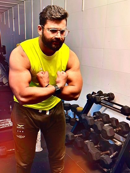 Flexing in front of the dumbbell rack. A well-defined physique is a clear indicator of the hard work and smart training that I advocate.