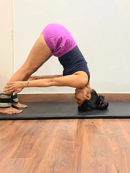 Prasarita Padottanasana (Wide-Legged Standing Forward Bend) is shown here with ankle weights. The weights help to ground the feet and intensify the stretch in the hamstrings and inner thighs.