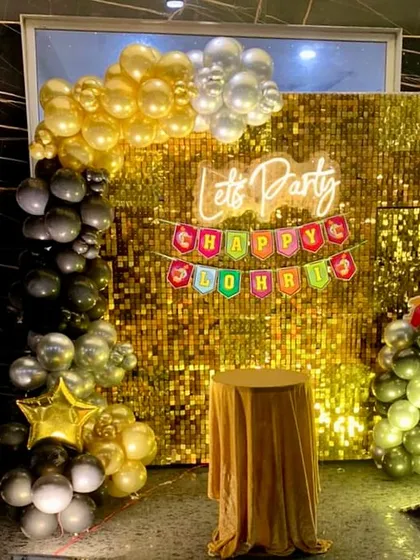 A glamorous Lohri party setup featuring a brilliant gold sequin wall that creates a stunning photo backdrop. We combined a 'Let's Party' neon sign, a 'Happy Lohri' banner, and a large marquee number '1' to celebrate a first Lohri in style.