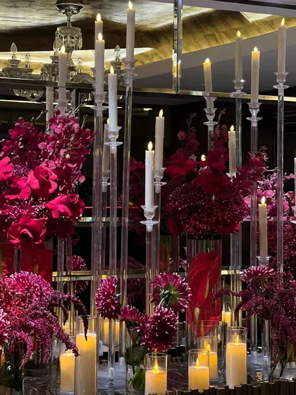 The decor featured opulent details like crystal chandeliers draped in red velvet, cascading floral arrangements, and candelabras that added to the romantic, high-end feel of the celebration.