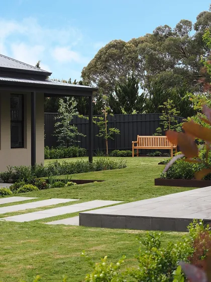A view from the side of the house, showing how the stepping stones lead from the patio area across the lawn. The design is simple, elegant, and highly functional.