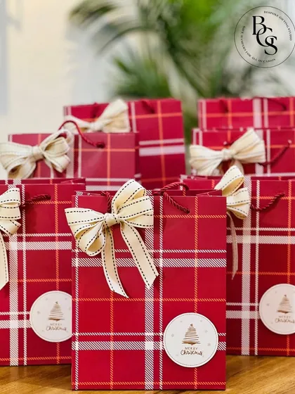Simple yet festive red plaid Christmas gift bags. Each bag is adorned with a custom "Merry Christmas" sticker and a delicate bow, making them a great option for distributing corporate holiday goodies or party favors.