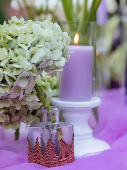 A detail shot of a single candle and a small, artistic vase, part of the intricate table decor.