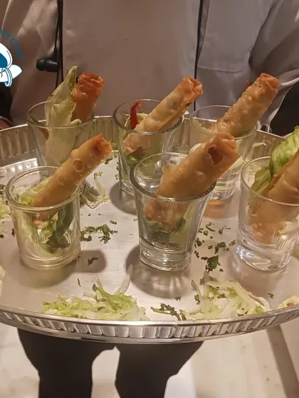 Crispy spring rolls served in shot glasses, a stylish presentation for a house party.