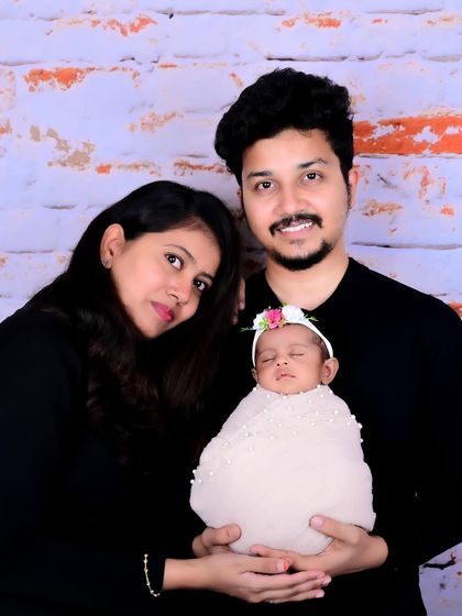 The first family photo. This portrait captures the quiet joy of new parents holding their sleeping newborn, a simple and timeless image that marks the beginning of their journey as a family.