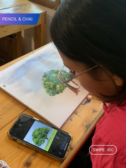 A student practices painting a tree from a reference photo, focusing on capturing its volume and texture. This exercise is crucial for building realistic landscape skills.