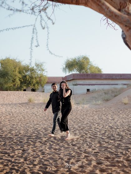 A candid moment of the couple walking and laughing in the desert, capturing their natural connection.