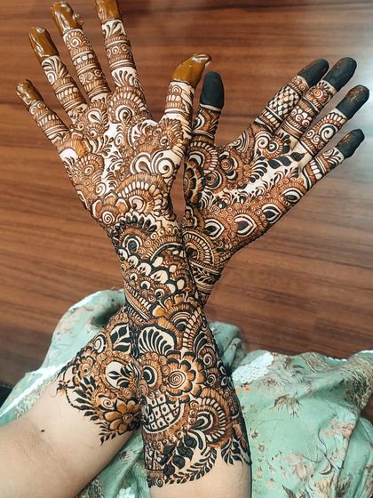 An intricate and dense bridal design that fills the hands and arms completely. The patterns are a mix of traditional Indian motifs, creating a rich and luxurious look.