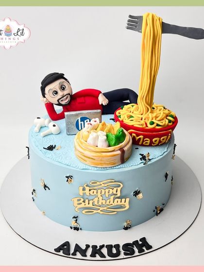 A personalized cake for Ankush, featuring all his favorite things: a caricature of himself, Maggi noodles, momos, and his HP laptop.