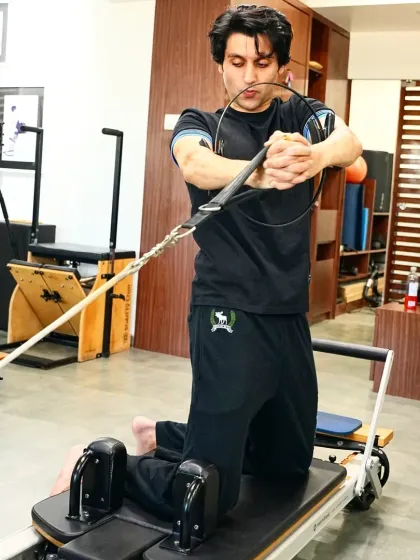 Real men do Pilates. A client works on a kneeling rotational exercise on the reformer, a movement that builds powerful obliques and improves spinal mobility, essential for rotational sports like golf or tennis.