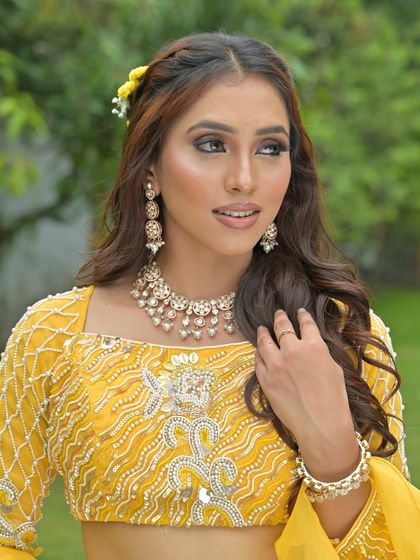 A bright and sunny look for a Haldi ceremony. The model is wearing a delicate pearl and Polki necklace set with a vibrant yellow lehenga.