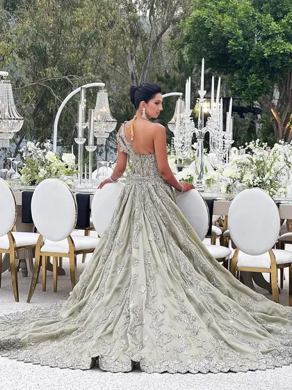 The bride posing in her magnificent gown, her French knot updo adding to the overall drama and elegance of the look.